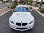 Front view of a white 2012 BMW M3 Convertible with 102,000 miles parked in a landscaped area.