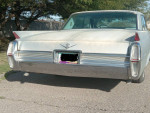 Rear view of a 1964 Cadillac Sedan DeVille, showcasing classic tail fins and chrome detailing.