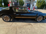 1980 Chevrolet Camaro Z28 4 Speed, black exterior, parked at gas station with clean wheels and golden stripes.
