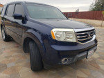 2014 Honda Pilot EX-L in blue, parked on patterned pavement, showcasing its exterior design.