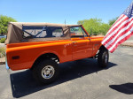 1971 Chevrolet K5 Blazer in vibrant orange with a canvas top, displaying an American flag on a sunny day.