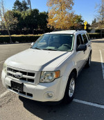 2012 Ford Escape Hybrid in a parking lot with autumn trees, showcasing low mileage and reliable condition.