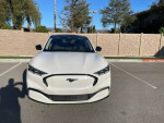 Front view of a white Ford Mustang Mach-E Premium in pristine condition, parked in a lot.