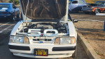 Front view of a white 1989 Ford Mustang LX 5.0 with the hood open, showcasing its clean engine bay.