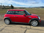 Red 2010 Mini Cooper S parked beside a field, showcasing its clean exterior and sleek design