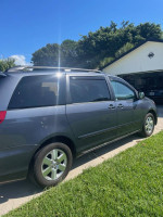 2009 Toyota Sienna LE minivan parked in grass, showcasing exterior features and good condition.