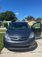 2009 Toyota Sienna LE in gray, parked with doors open, clear sky, ideal for families with 7-passenger capacity.