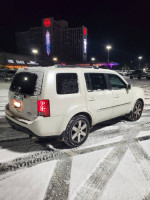 2015 Honda Pilot Touring 4WD parked in snowy conditions, showcasing its sleek design and clean lines.