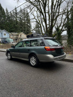 2001 Subaru Outback wagon in excellent condition parked on the street with a roof rack, showcasing its clean exterior.