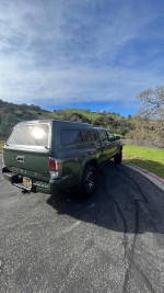 2022 Toyota Tacoma TRD Off Road 4WD parked on a scenic road with a camper shell and high clearance.