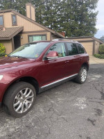2008 Volkswagen Touareg in burgundy, parked outside a house, showcasing its sleek design and features.