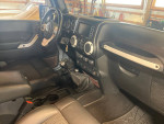 Interior view of a well-maintained 2012 Jeep Wrangler Unlimited Rubicon with leather seats and manual gear shift.