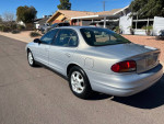 1999 Oldsmobile Intrigue GL in good condition, silver, parked on a residential street, showcasing its rear and side view.