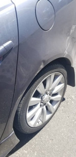 Close-up of a 2011 Mitsubishi Ralliart showing alloy wheels and minor scratches on the body.
