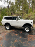 1972 International Scout in white, parked on a wet road with trees in the background, perfect for restoration.