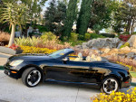 2005 Lexus SC430 convertible in black parked by colorful flowers, showcasing luxury and style.