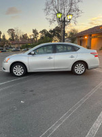 2014 Nissan Sentra SV in silver color parked in a lot, showcasing its clean and well-maintained exterior.