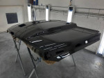 Refinished black cowl hood for a 2018 Ram 2500, showcasing a glossy surface in a workshop.