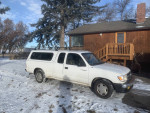 White Toyota Tacoma Xtracab parked in snowy driveway, showcasing its rugged appeal and manual transmission.