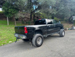 2006 Chevrolet Silverado 1500 in black with off-road tires parked on a rural road.