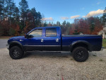 Side view of a blue Ford F350 King Ranch 4x4 truck with aftermarket wheels and tires.